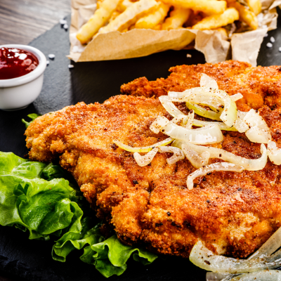 Goudbruin gebakken kipschnitzel met frietjes en salade.
